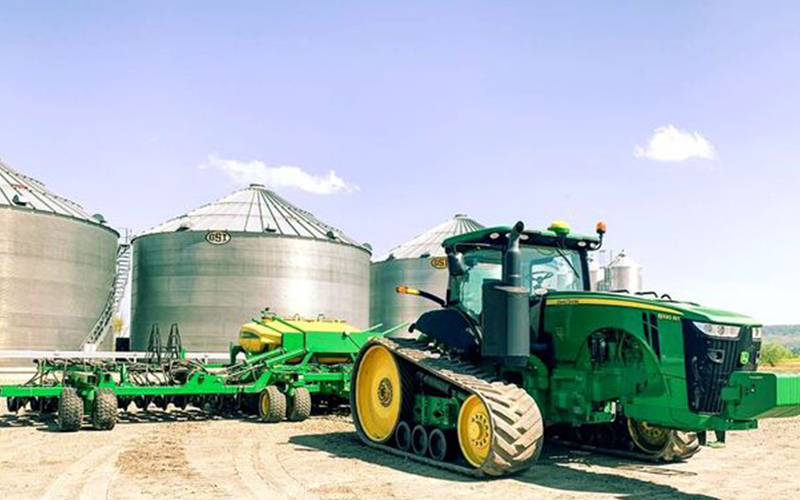 tractor next to large grain bins