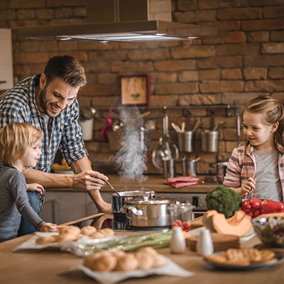 man cooking rice in kitchen with his daughters